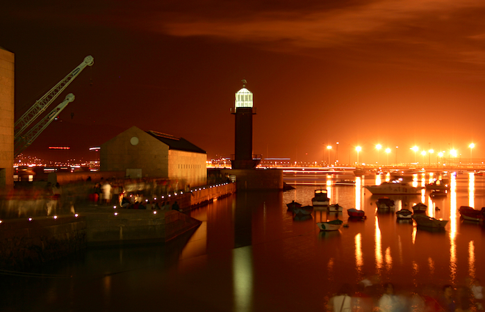 A reddish summer's evening in Vigo, with the shadows of people enjoying themselves on the harbour.