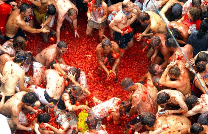 Crowds of half-naked guests party in the street and throw tomatoes everywhere. 
