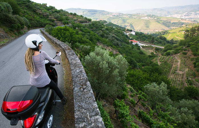 A woman travels by scooter overlooking the Douro Valley 