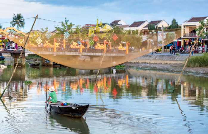 A man travels in a traditional Vietnamese fishing boat in Hoi An, Vietnam