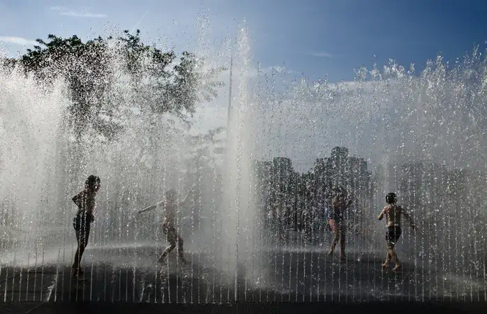 Four children in partial silhouette play in fountain on Southbank, London.