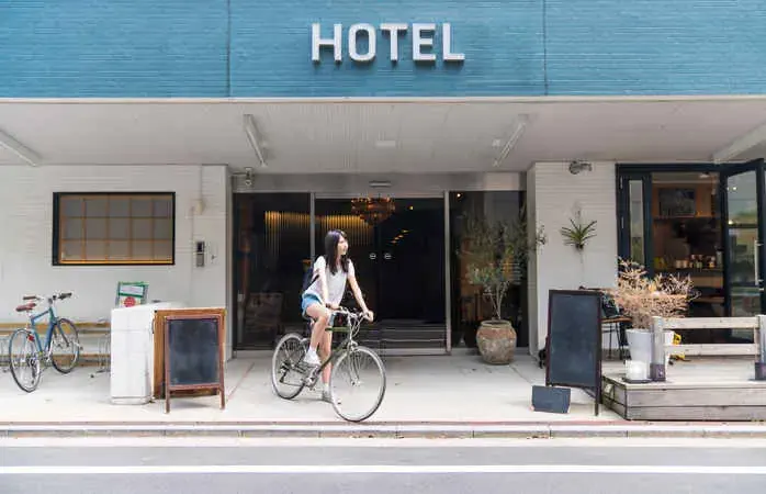 Woman in front of a hotel with a rental bicycle looking at a map on her smartphone