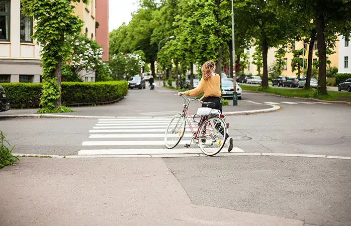 A girl with bicycle crosses the street in Oslo, Norway; Shutterstock ID 722285053; Purpose: Eco friendly destinations; Brand (KAYAK, Momondo, Any): momondo
